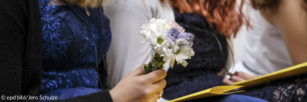 Eine Konfirmandin hält einen Strauß Blumen in der Hand