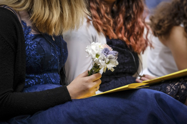 Eine Konfirmandin hält einen Strauß Blumen in der Hand